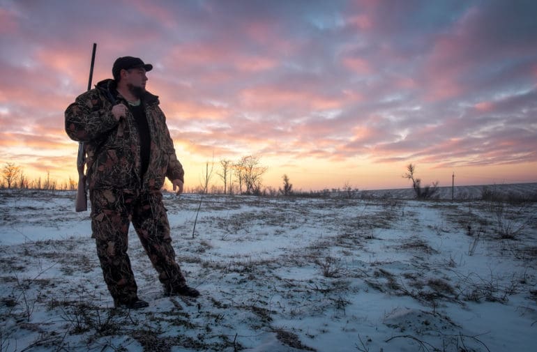 Winter Hunting At Sunrise. Hunter Moving With Shotgun And Lookin