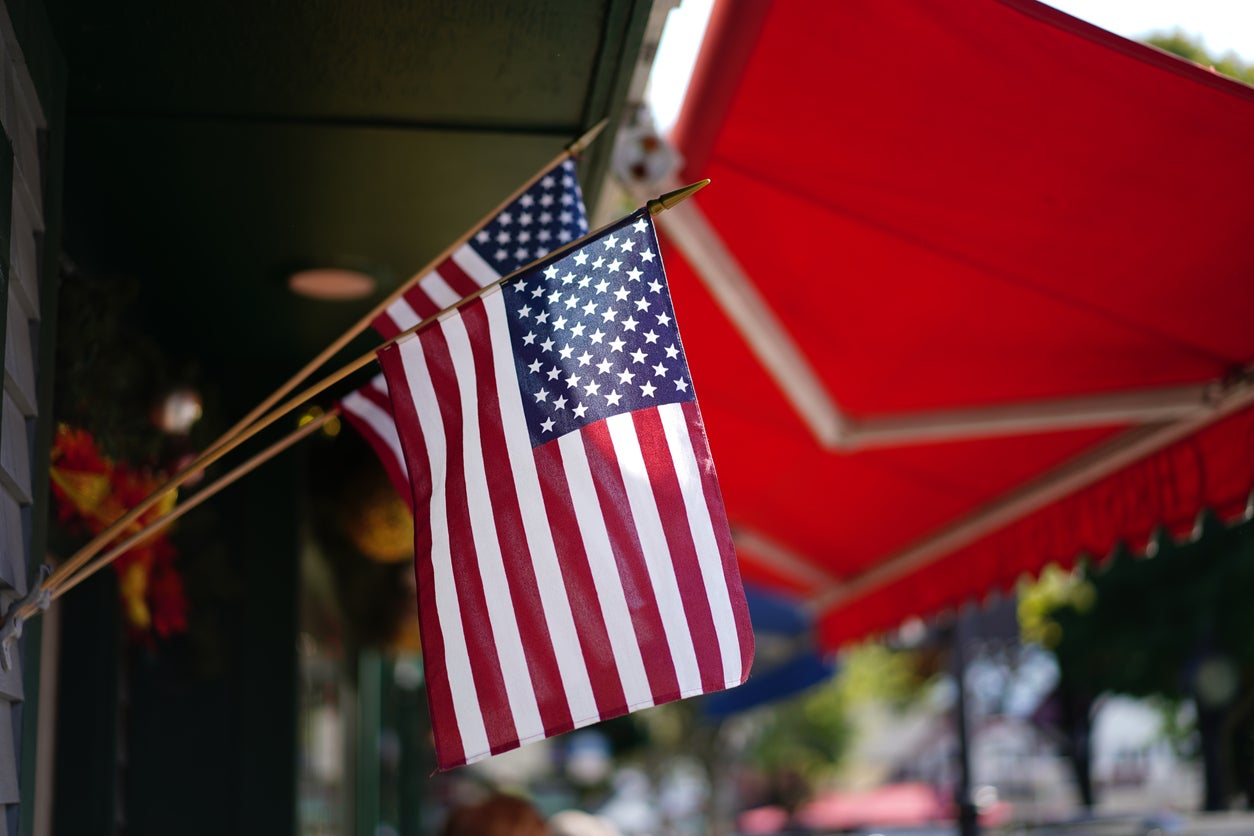 American flags hanging outside a storefront with red awnings, symbolizing patriotism and constitutional values in support of the Second Amendment.