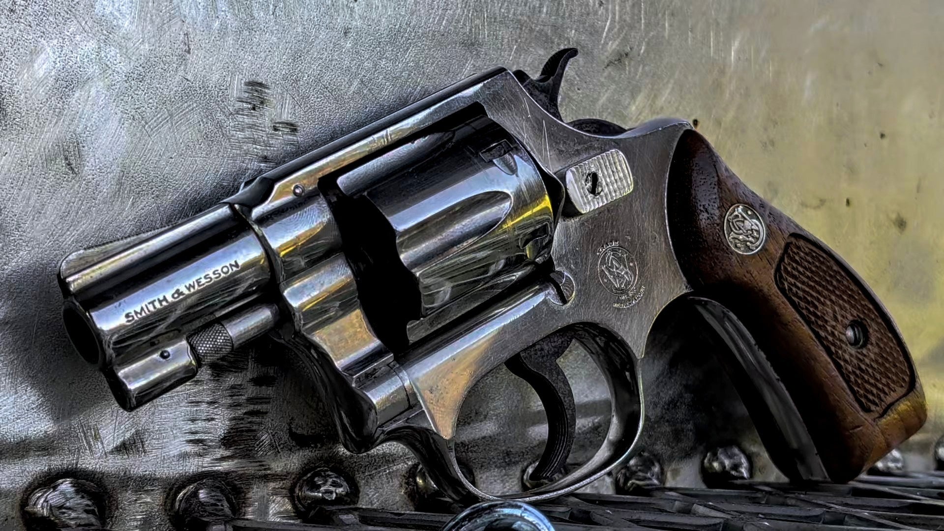 Nickel-finished Smith & Wesson Pre-Model 30 snub-nose revolver with a short barrel, six-shot cylinder, and brown wooden grips resting on a metal surface.