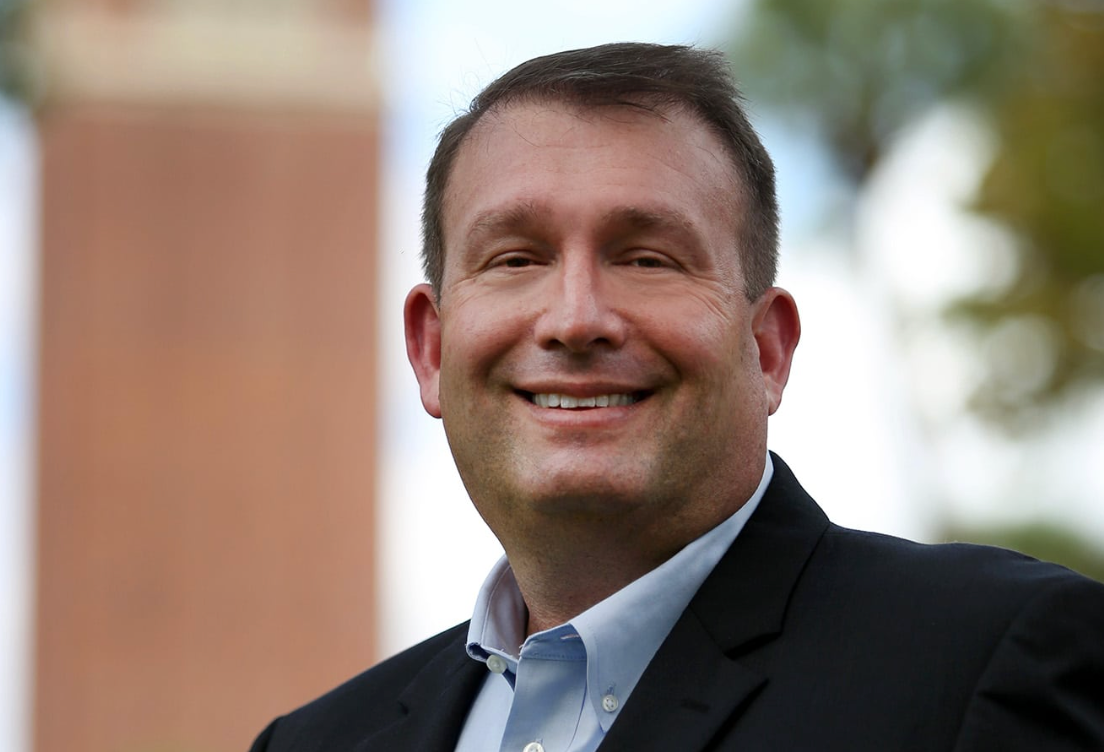 Florida State Attorney Brian Kramer wearing a dark blazer and light blue collared shirt in an outdoor portrait.