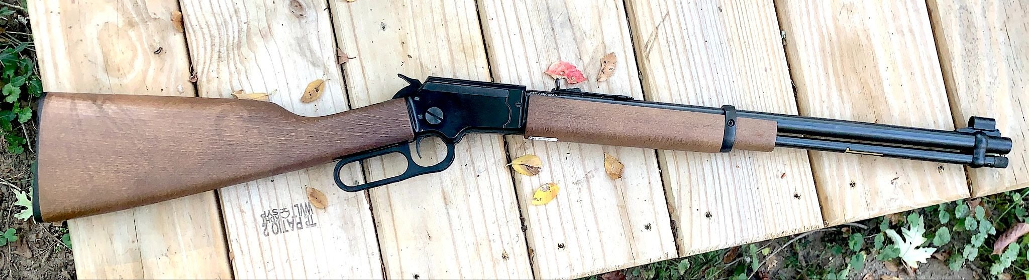 Chiappa LA-322 Takedown .22 LR lever-action rifle with a wooden stock and forearm, black receiver, and tubular magazine resting on a wooden table.