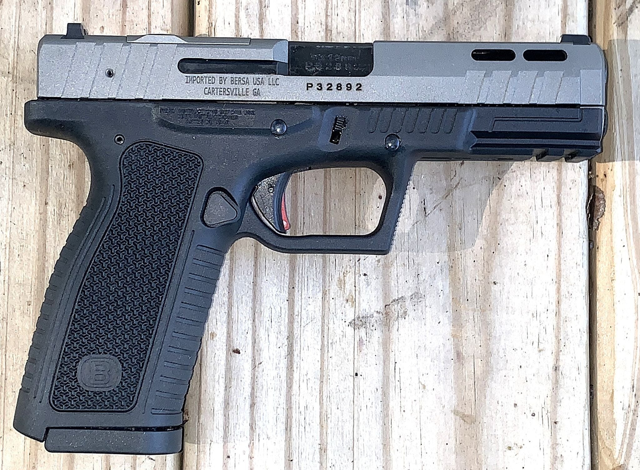 Bersa BP9FS full-size striker-fired 9mm pistol with black polymer frame, textured grip and optics-ready slide on a wooden surface.
